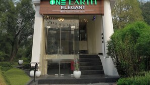 A modern building with a sign reading "ONE EARTH ELEGANT" and a tagline "Where happiness meets nature." - One Earth Elegant Amritsar (Amritsar)