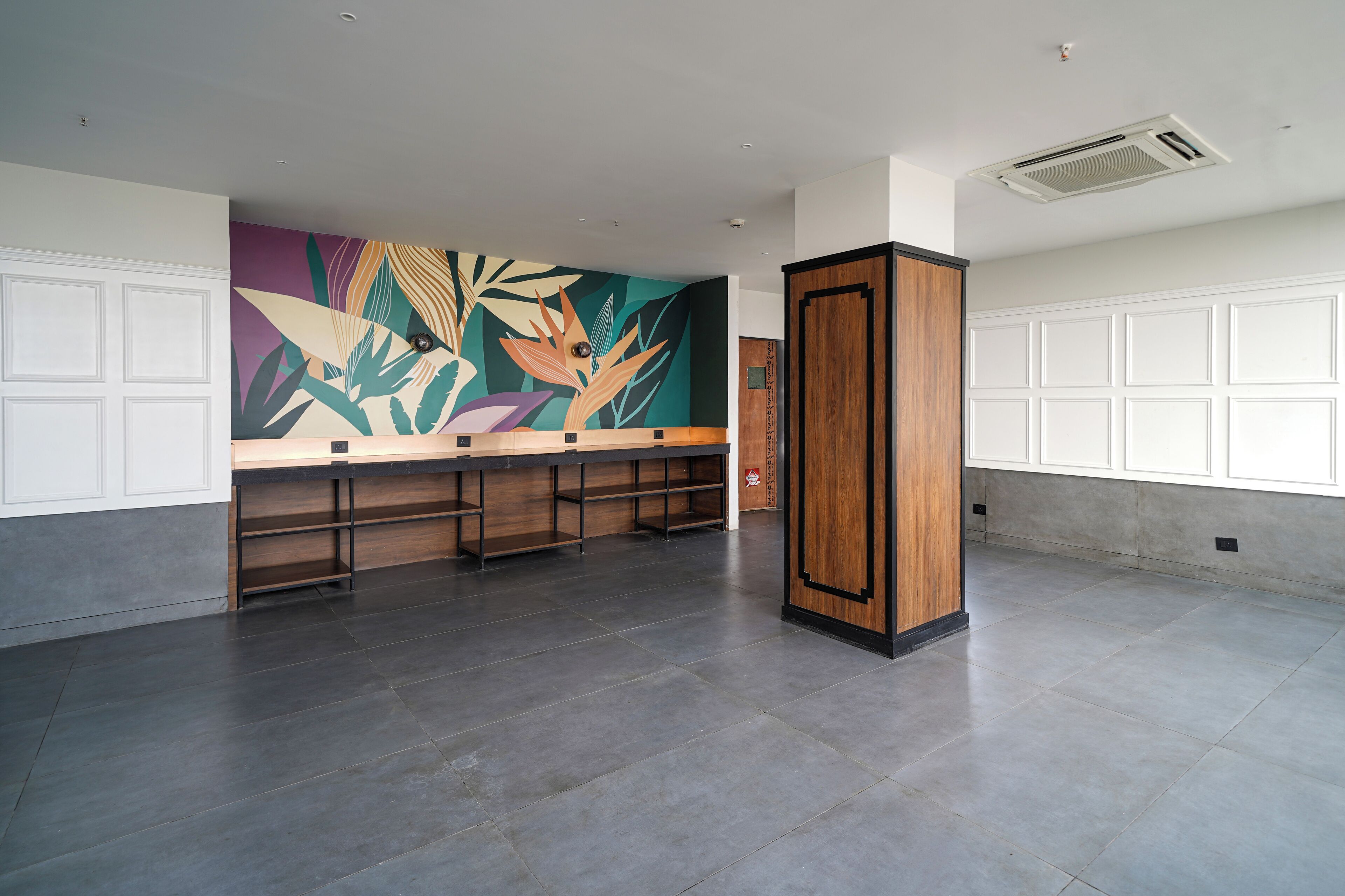 Un vestíbulo espacioso con una larga recepción, un gran mural abstracto y una columna de madera.