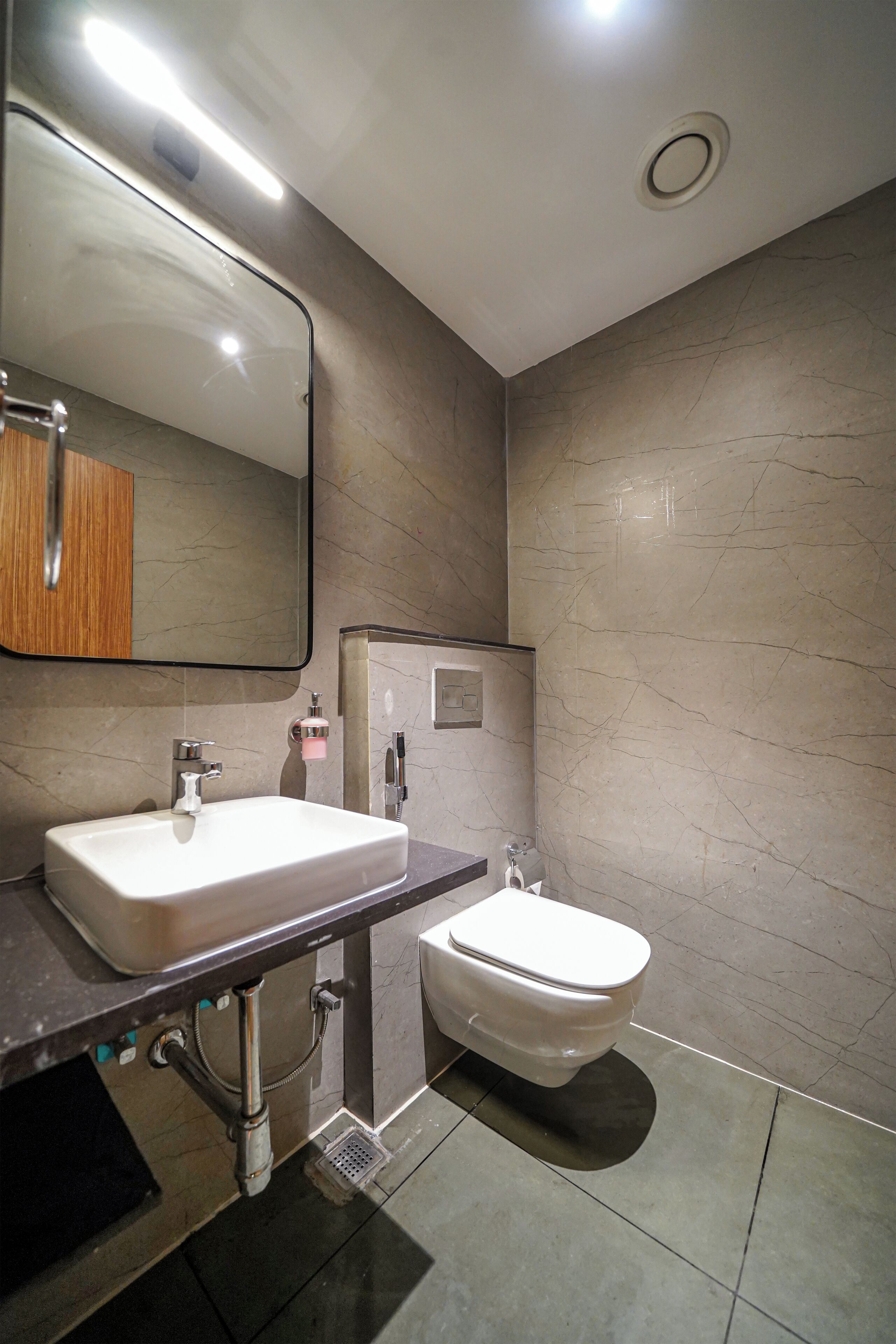Une salle de bain moderne avec un grand miroir, un lavabo, un bidet et des toilettes.