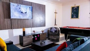 A modern living room with a flat-screen TV, a pool table, a sofa, and a chair. - Micasa Haven (Lekki)