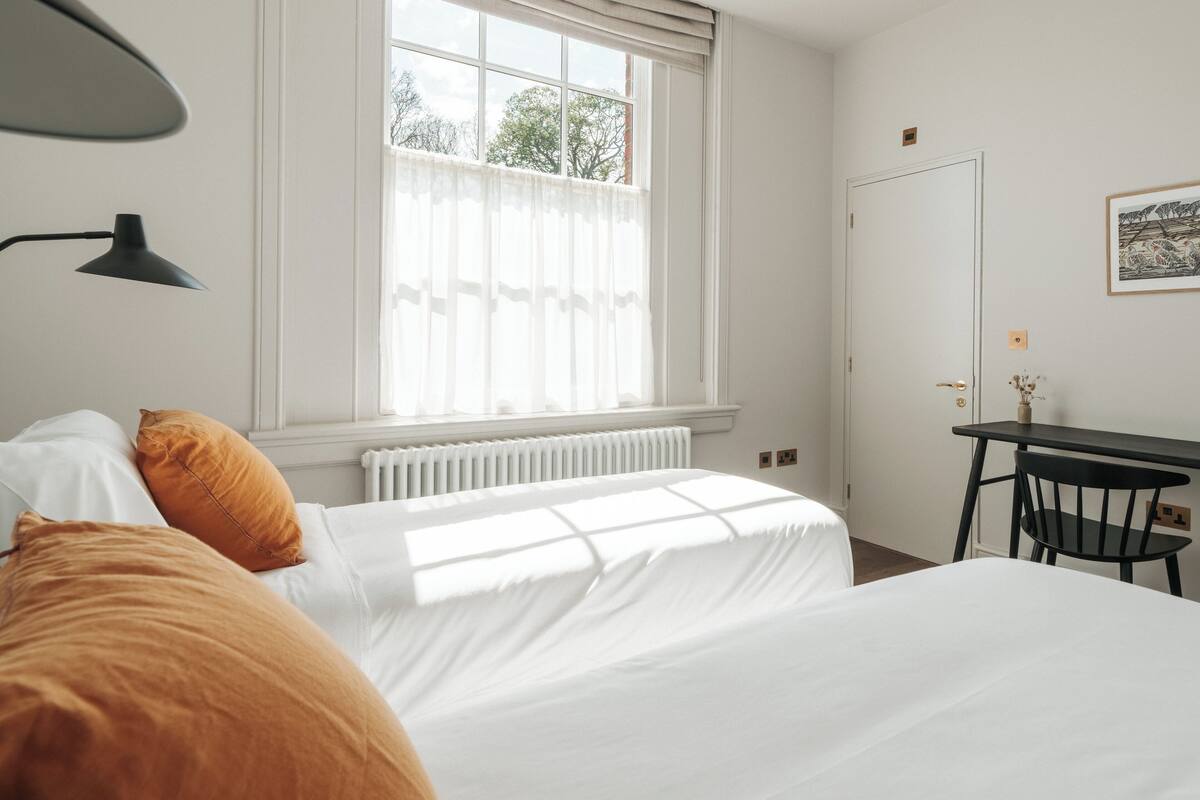 A bedroom with a bed, a desk, and a window.