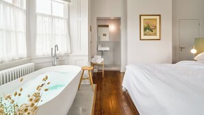 Ein modernes Badezimmer mit einer freistehenden Badewanne, einem Holzschemel und einem Handtuchhalter.