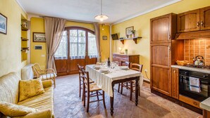 Un comedor acogedor con una mesa dispuesta para cuatro, armarios de madera y una cocina con estufa.