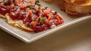 A plate with grilled bread and a tomato-based topping. - Posada La Rosaleda (Los Roques)