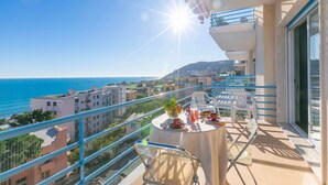 A balcony with a table set for two, overlooking a coastal view. - Sofy Apartment - Sea View (Sanremo)