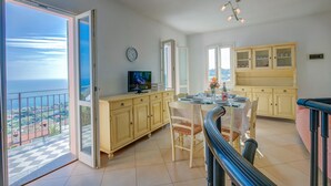 A spacious dining area with a balcony overlooking the sea, a kitchen with yellow cabinets, and a modern chandelier. - Palms Villa - Sea View (Sanremo)
