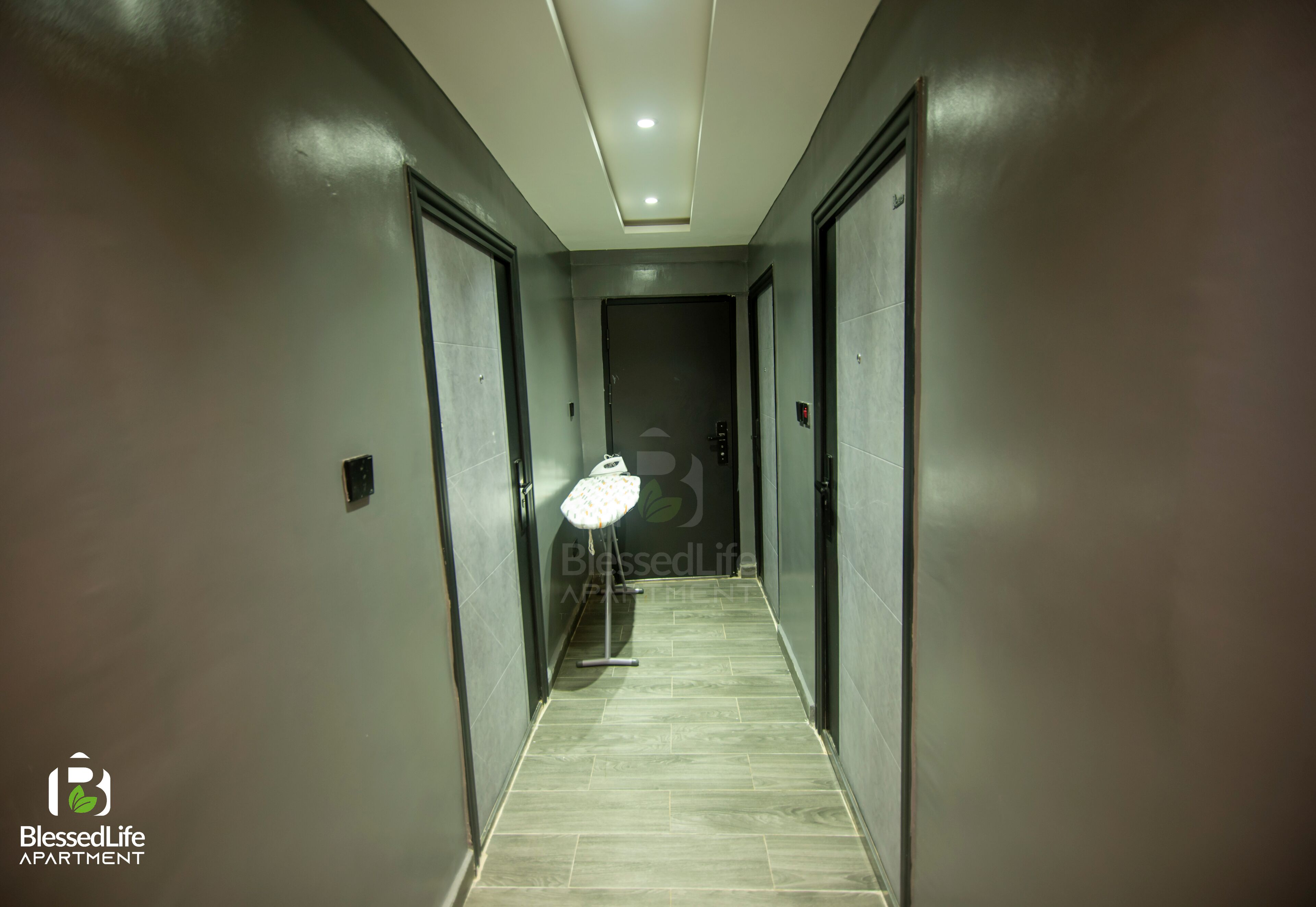 Un couloir avec un luminaire, une poubelle et une porte au fond.