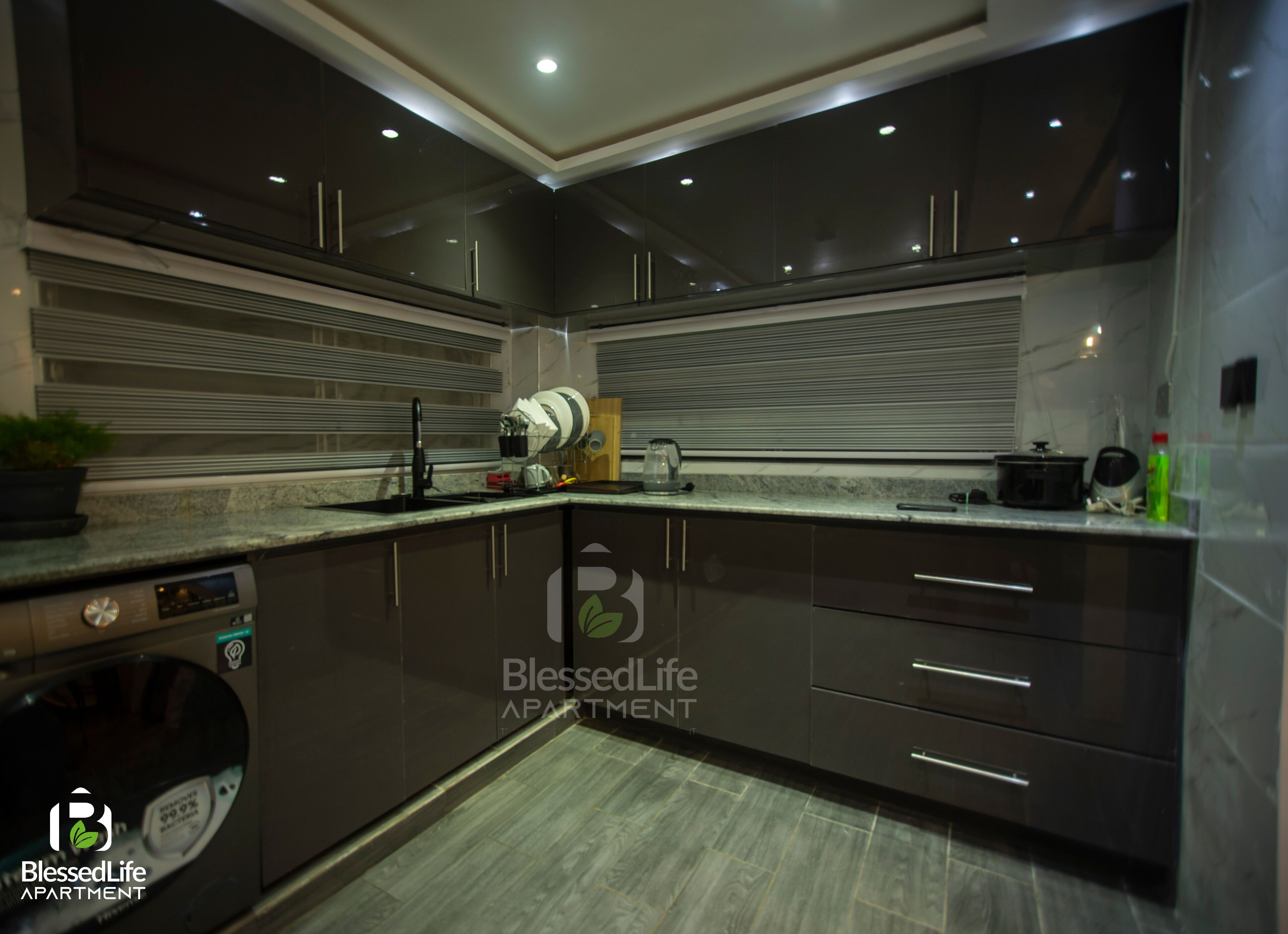 A modern kitchen with dark cabinetry, a built-in dishwasher, and a countertop with various appliances.