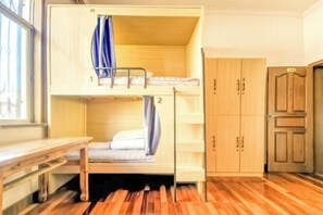 Una cama litera con escritorio, armario de madera y una puerta con número.