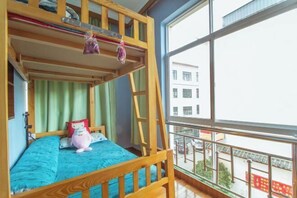 Habitación con literas y vistas a un edificio a través de un amplio ventanal.