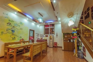 A dining area with wooden furniture, a wall with a map, and a staircase with a railing. - Jianying (Lijiang)