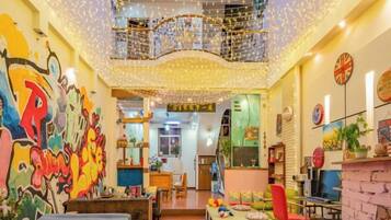 A brightly lit room with a high ceiling, string lights, and a colorful mural on the wall.