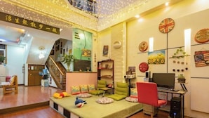 A cozy living room with a green sofa, a red chair, and a computer desk. There is a staircase in the background leading to an upper level. - Jianying (Lijiang)