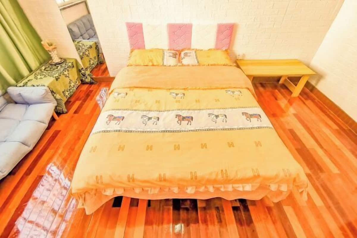 A bed with a patterned bedspread, a bedside table, and a chair.