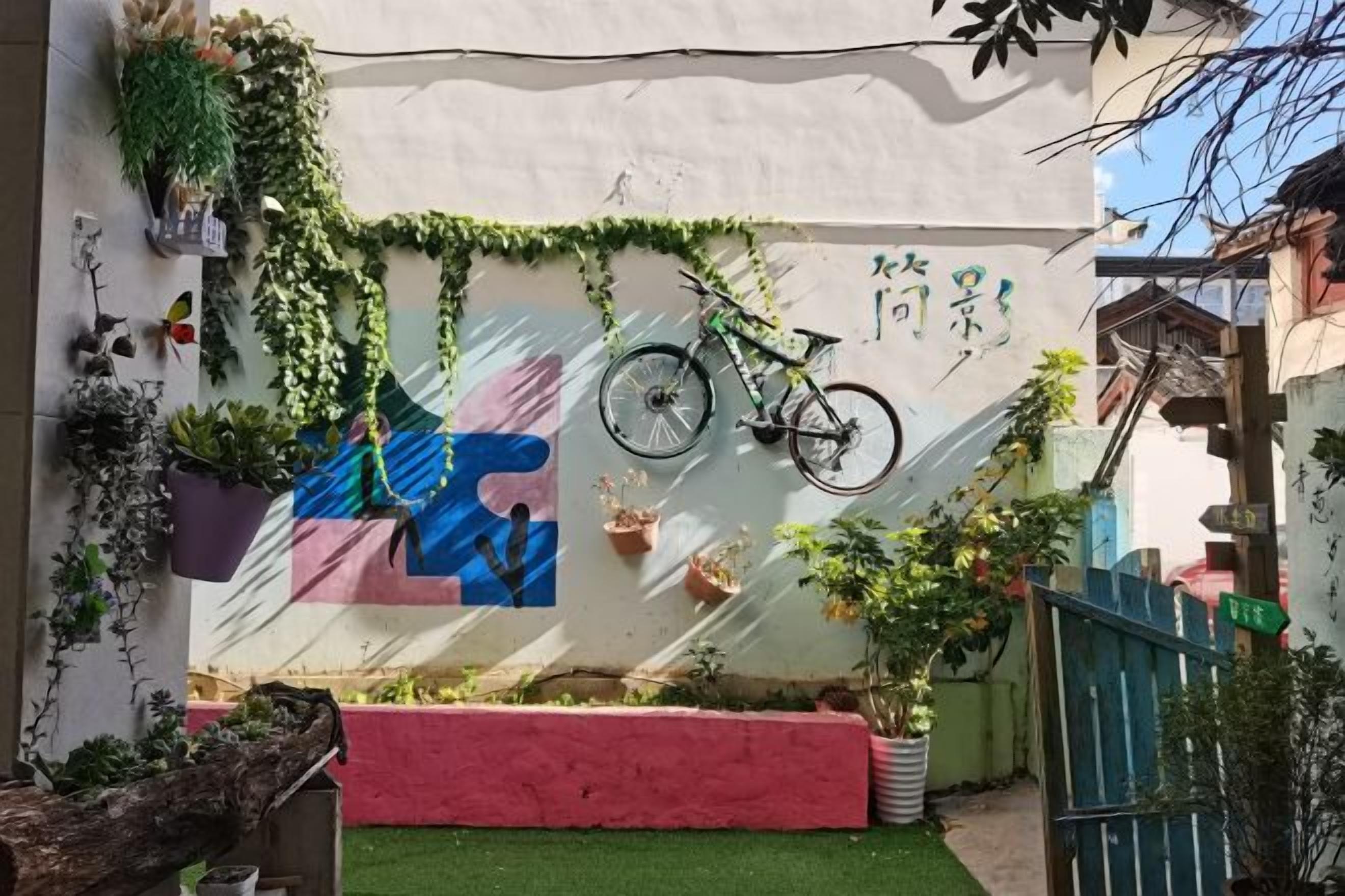 A courtyard with a bicycle, potted plants, and a colorful mural.