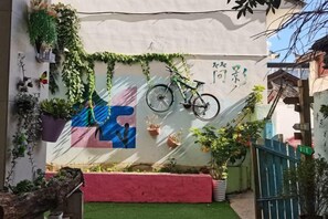 A courtyard with a bicycle, potted plants, and a colorful mural. - Jianying (Lijiang)