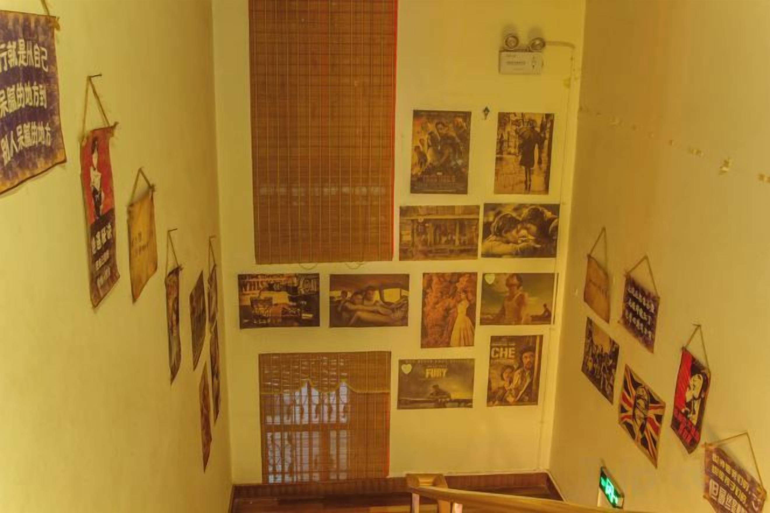 A staircase with a handrail, surrounded by various framed pictures and posters on the walls.