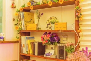 Une bibliothèque avec des livres, des fleurs et des objets décoratifs.