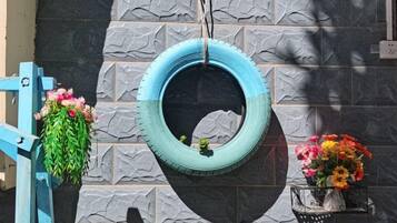 A tire hanging as a planter with flowers, a blue gate, and a wall with a stone pattern.