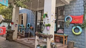 A covered outdoor area with a wooden bench, hanging plants, and a tire wall. - Jianying (Lijiang)