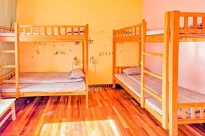 A room with two bunk beds, wooden flooring, and a small table. - Jianying (Lijiang)