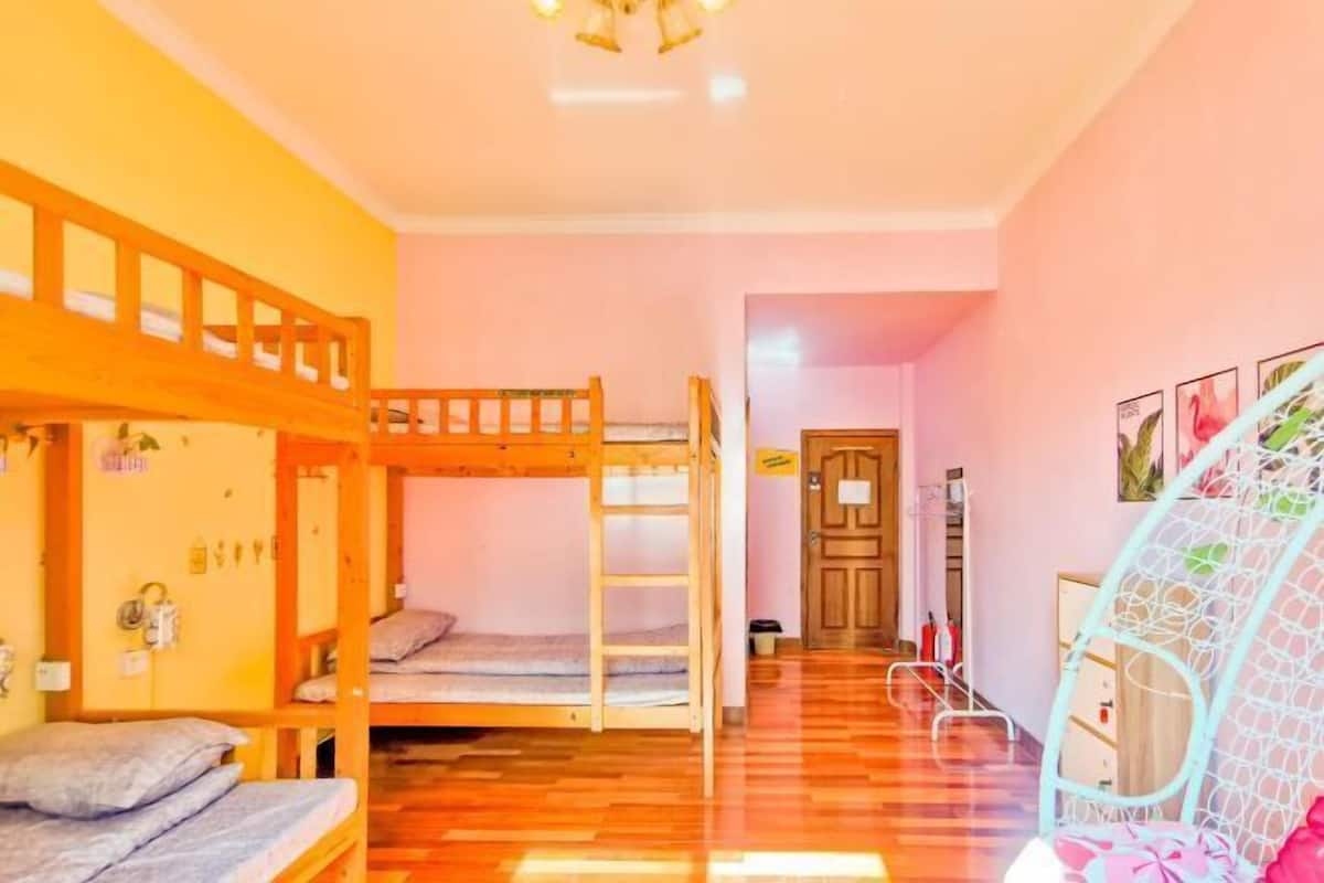 A room with bunk beds, a wooden ladder, a door, and a white chair.