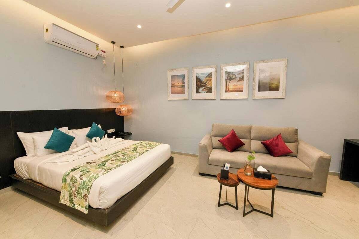 Ein Hotelzimmer mit einem Bett, einem Sofa und einem kleinen Tisch. An der Wand hängen gerahmte Bilder.