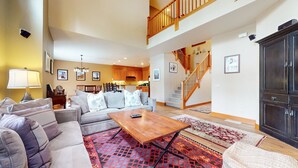 A spacious living room with a sofa, coffee table, and a staircase leading to an upper level.