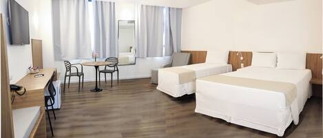 Une chambre d’hôtel avec deux lits, un bureau, une chaise et une petite table.
