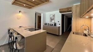 Et moderne køkken med en central ø, trælofter og et minimalistisk design.