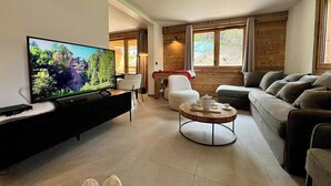 En moderne stue med et fladskærms-tv, et rundt sofabord og en sofa.