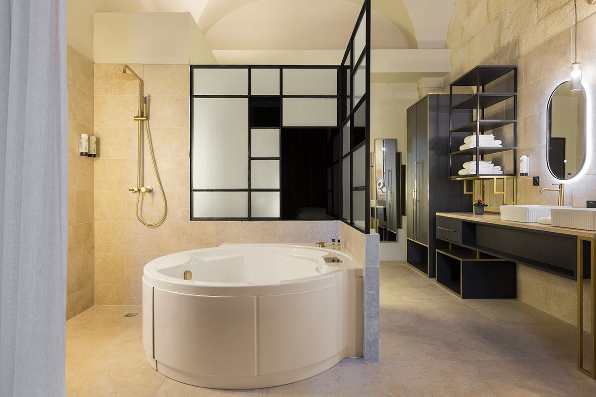 Un baño moderno con una bañera independiente, ducha a ras de suelo y tocador con espejo.