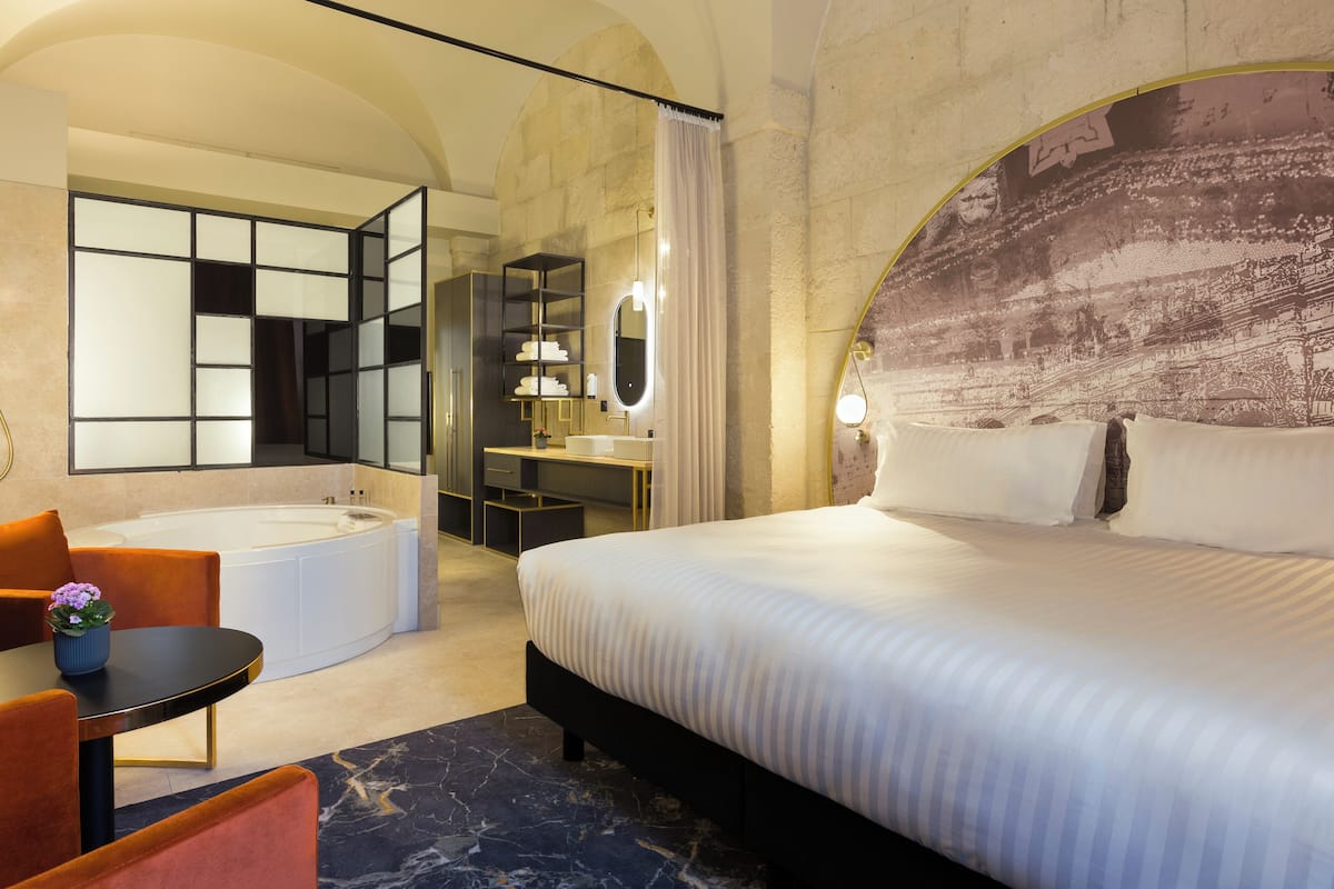 Een hotelkamer met een groot bed, een aparte badkamer met bad en een bureau met een stoel.