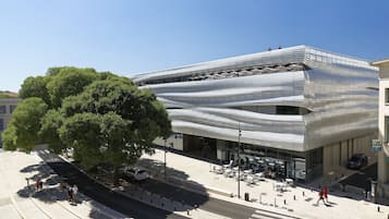 A modern building with a unique wavy facade, outdoor seating area, and a café.