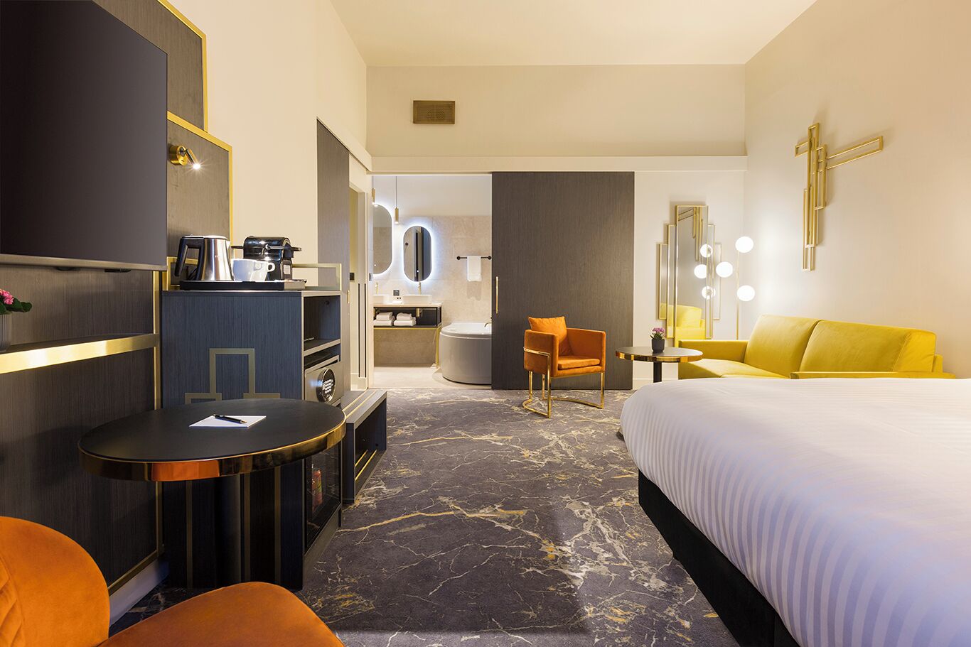 Une chambre d’hôtel équipée d’un lit, d’un bureau, d’une chaise, d’un canapé, d’une salle de bain et d’une télévision.