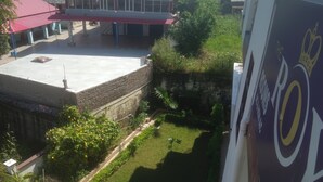 Ein Innenhof mit Backsteinmauer, kleinem Garten und einem Gebäude mit rotem Dach.