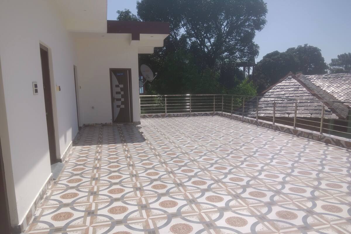 A covered outdoor area with patterned flooring, a door labeled "PANTRY," and a metal railing.