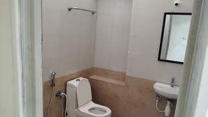 A small, modern bathroom with a toilet, shower, and sink. - SANKARA RESIDENCY (Kanchipuram)