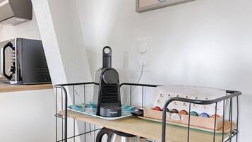 Una zona de cocina con cafetera, hervidor y una bandeja con diversos objetos.
