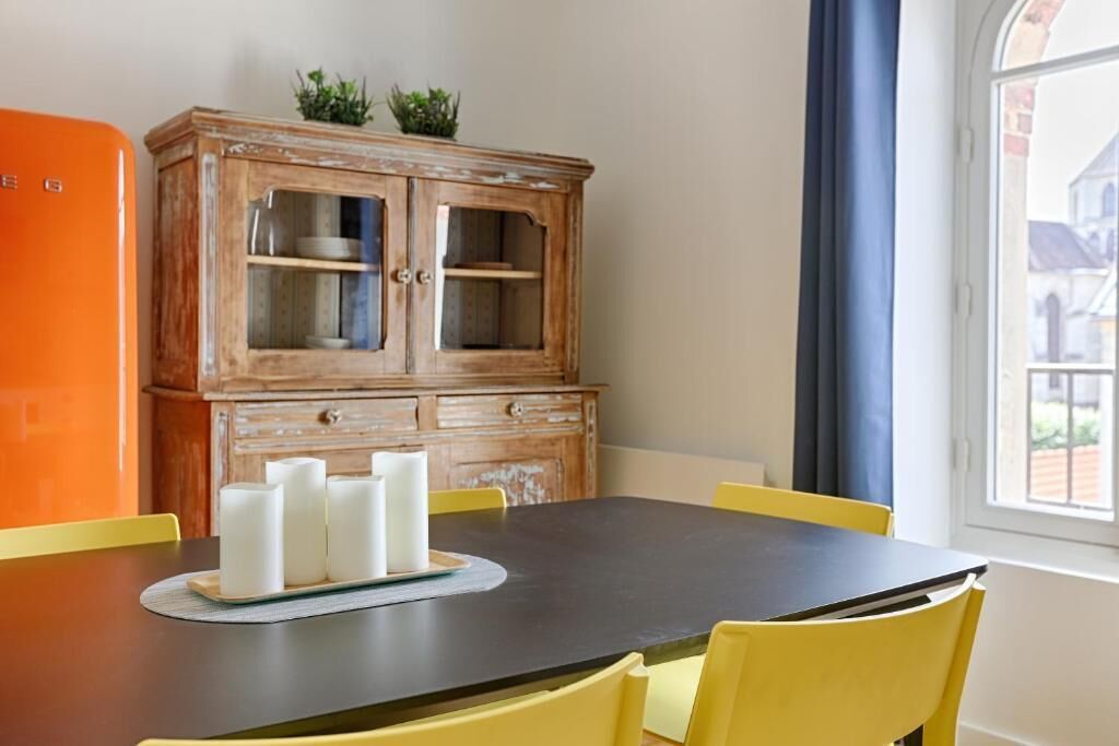 A dining area with a wooden cabinet, a black table, and yellow chairs.