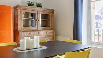 A dining area with a wooden cabinet, a black table, and yellow chairs.