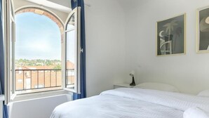 A bedroom with a large bed, a nightstand, a lamp, and two framed pictures on the wall. - Le Magnolia - Proche de Disneyland (Lagny-sur-Marne)