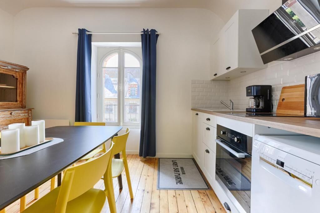 Una cucina compatta con un tavolo da pranzo, sedie gialle, una macchina per caffè e un forno a microonde.