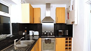 A kitchen with wooden cabinets, a stainless steel range hood, a built-in oven, a microwave, and a sink. - Cozy Birmingham House - Nec Hs2 Jlr Airport (Birmingham)