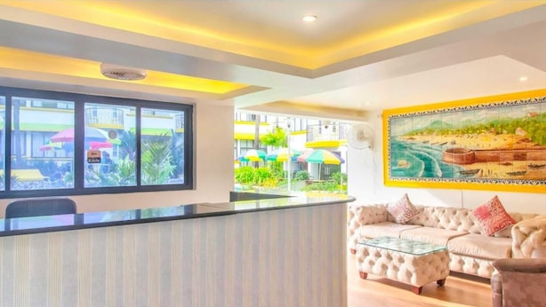 A hotel lobby with a reception desk, a sofa, and a painting on the wall. - POM Holidays (Calangute)