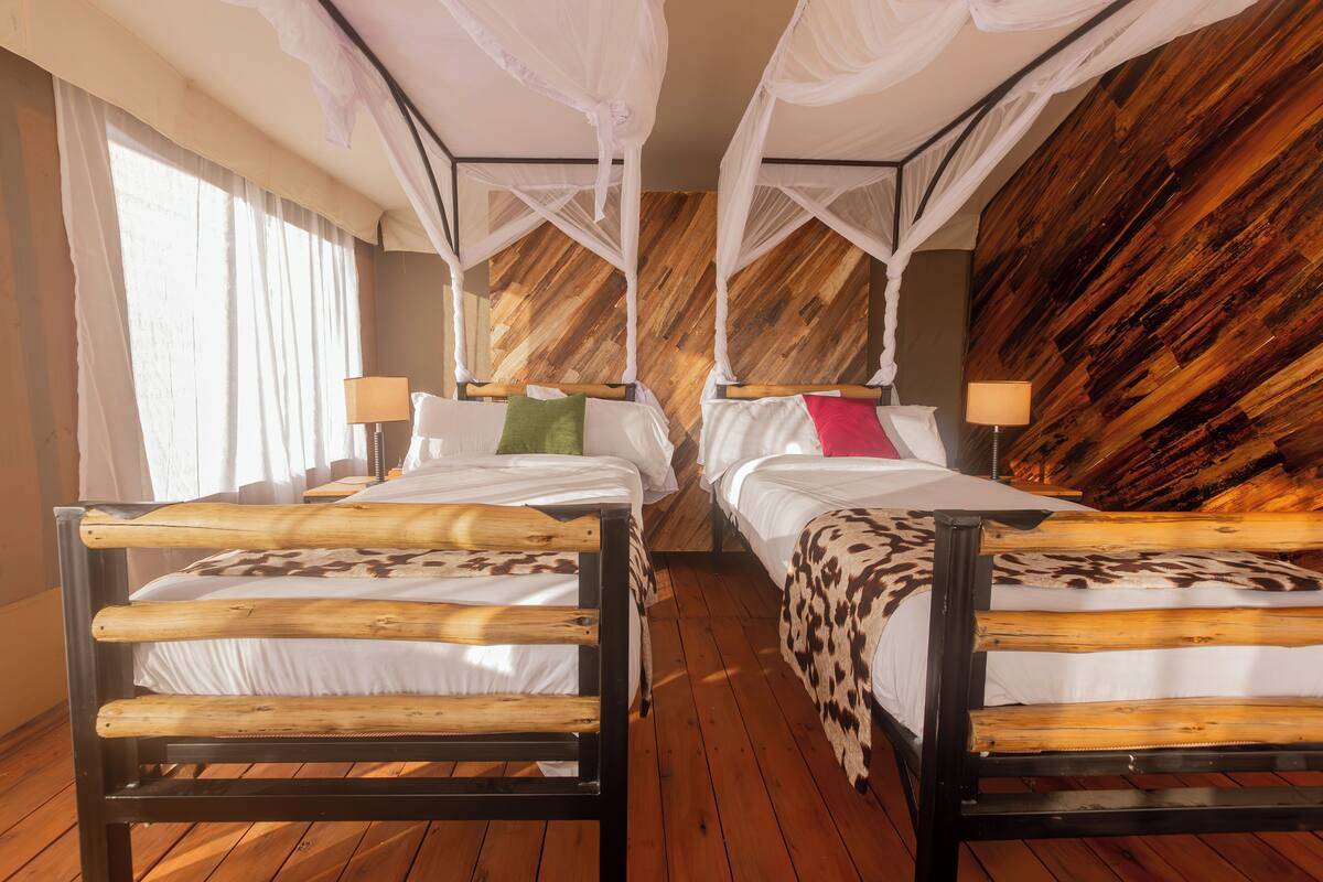 A room with two wooden beds, each with a canopy and pillows.