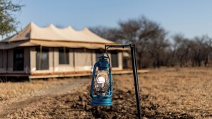 Un farol azul en un campo con tiendas de campaña al fondo.