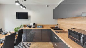 Eine moderne Küche mit dunklen Schränken, einer Holz Arbeitsplatte, einem eingebauten Backofen und einem flachbildfernseher an der Wand.
