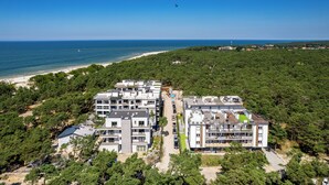 Ein moderner Apartmentkomplex mit mehreren Gebäuden, einem Strand und freiem Blick auf das Meer.