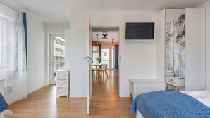 Ein Hotelzimmer mit Bett, Fernseher, einem Gemälde und Blick auf den Balkon.